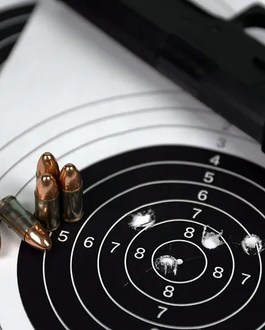 Handgun, 9mm rounds and a paper target with shot grouping