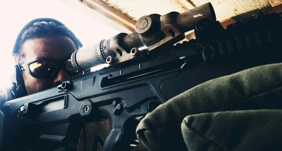 McConnell Trapp sighting an AR-style rifle through a magnified optic