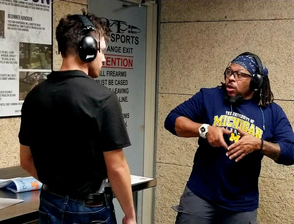 McConnell Trapp coaching a student on the firing line at an indoor range