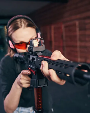 Student aiming an AR-15 with a red-dot optic at the indoor range